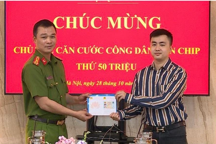 Thượng tá Tô Anh Dũng, Phó Cục trưởng Cảnh sát quản lý hành chính về trật tự xã hội tặng chiếc thẻ thứ 50 triệu cho công dân Trần Quang Huy.