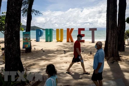 Du khách dạo chơi trên bãi biển ở Phuket, Thái Lan ngày 14/8/2021. (Ảnh: AFP/TTXVN)