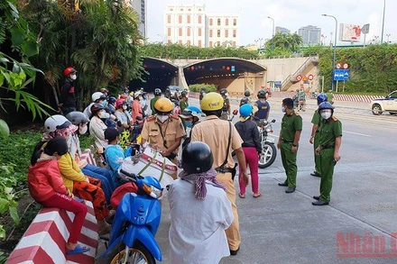 Các cơ quan chức năng tuyên truyền, vận động người dân quay về nơi ở khi đang trên đường về quê bằng xe máy tại khu vực hầm Thủ Thiêm, TP Thủ Đức. (Ảnh: QUANG QUÝ)