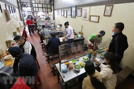 Quán ăn trong nhà lắp tấm chắn giữa các vị trí ngồi bảo đảm phòng, chống dịch Covid-19. (Ảnh: TTXVN)