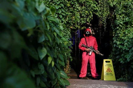 Bộ trang phục màu đỏ hồng cùng mặt nạ đen của nhân vật trong Squid Game xuất hiện tại Jakarta, Indonesia. (Ảnh: Reuters)