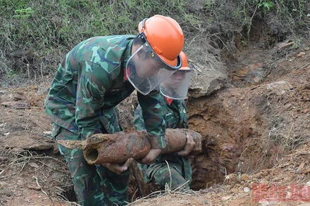 Lực lượng chức năng tiến hành rà phá vật nổ trong vườn nhà ông Nguyễn Văn Nho.