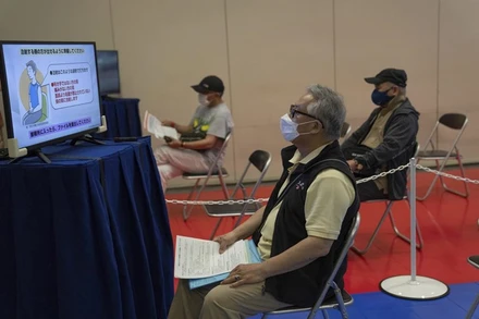 Người dân theo dõi hướng dẫn tiêm vaccine ngừa Covid-19 tại trung tâm tiêm chủng ở Tokyo. (Ảnh: AP)