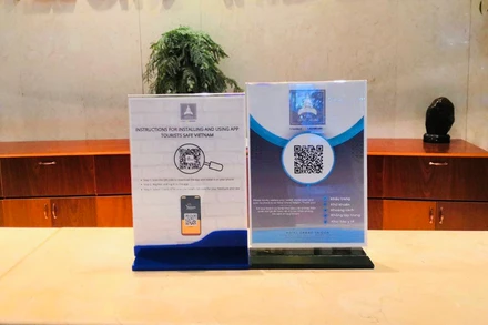 Thiết kế hướng dẫn khách du lịch tải và sử dụng ứng dụng “Du lịch Việt Nam an toàn” bằng 2 ngôn ngữ tiếng Việt – tiếng Anh tại quầy lễ tân của một khách sạn ở TP Hồ Chí Minh (Ảnh: Khách sạn cung cấp)