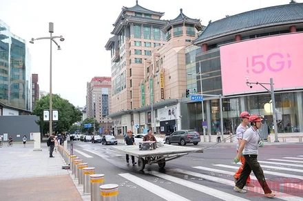 Người lao động không đeo khẩu trang đi qua một ngã tư. (Ảnh: VI SA)