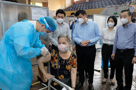 Bộ trưởng Nguyễn Thanh Long kiểm tra điểm tiêm ở nhà thi đấu Trịnh Hoài Đức, thăm hỏi những người tới tiêm. (Ảnh: Bộ Y tế)