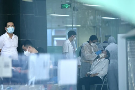 Lực lượng y tế lấy mẫu sàng lọc SARS-CoV-2 cho những người trong tòa D, Bệnh viện Việt Đức chiều 30/9. (Ảnh:TTXVN) 