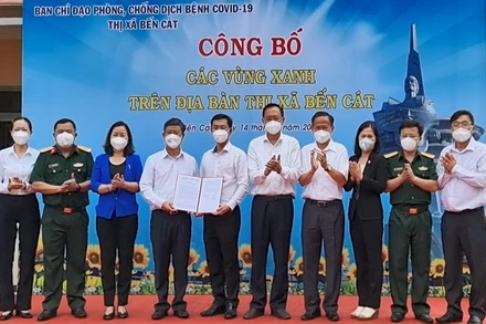 Chủ tịch UBND tỉnh Bình Dương Võ Văn Minh (thứ 4 từ trái sang) trao quyết định công bố “vùng xanh” cho lãnh đạo thị xã Bến Cát. 