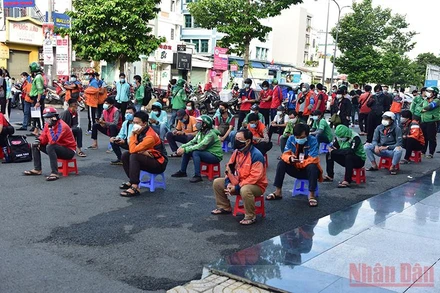 Các shipper xếp hàng dài chờ xét nghiệm tại một điểm ở phường 17, quận Gò Vấp. (Ảnh: QUÝ HIỀN)