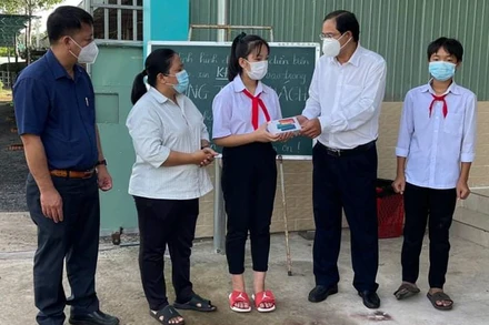 Phó Bí thư Thường trực Huyện ủy Châu Đức Nguyễn Tấn Bản (thứ 2, từ phải qua) trao thiết bị hỗ trợ học online cho em Nguyễn Uyên Nhi, học sinh lớp 7A3, Trường THCS Võ Trường Toản.