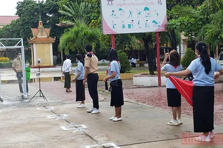 Học sinh một trường THPT tại Phnom Penh thực hiện đo thân nhiệt và khử khuẩn theo quy định.