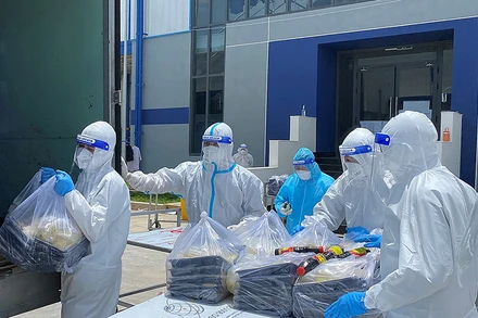 Các F0 khỏi bệnh hỗ trợ đưa cơm cho bệnh nhân tại Khu điều trị bệnh nhân Covid-19 Thới Hòa (Bình Dương).