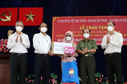 Nguyên Phó Thủ tướng Thường trực Chính phủ Trương Hòa Bình (thứ 2 từ trái qua) và đại diện các đơn vị trao tặng thiết bị học tập trực tuyến cho các em học sinh dân tộc Chăm tại quận 8.