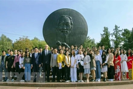 Sinh viên và khách mời chụp ảnh kỷ niệm bên tượng đài Hồ Chí Minh. (Ảnh: TTXVN)