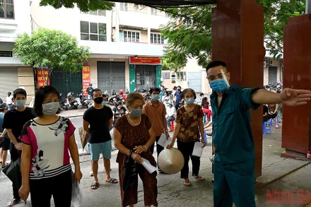 Phân luồng người dân xếp hàng tiêm vaccine Covid-19 tại Hà Nội. (Ảnh: DUY LINH)