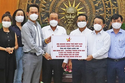 Đồng chí Trương Hòa Bình (thứ 4 từ trái sang) chứng kiến lễ trao vật tư y tế, nhu yếu phẩm và kinh phí hỗ trợ Long An chống dịch.