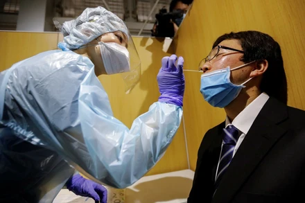 Một hành khách được lấy mẫu xét nghiệm trước khi ra nước ngoài tại sân bay Narita (Ảnh: REUTERS)