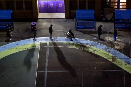 Cử tri xếp hàng tại sân chơi của một trường tiểu học tại bang New York từ sáng sớm để chờ điểm bỏ phiếu mở cửa. (Ảnh: AP)