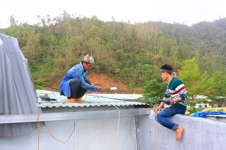 Anh Nguyễn Văn Thuận (bìa trái) sửa mái tôn cho một gia đình.