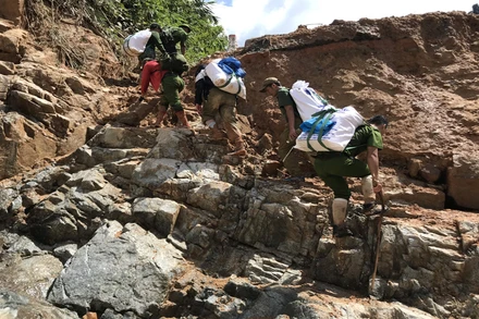 Lực lượng chức năng gùi hàng hóa vào tiếp tế cho người dân bị cô lập ở Phước Sơn, Quảng Nam. Ảnh: TẤN NGUYÊN.