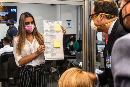 Các nhân viên bầu cử kiểm tra một lá phiếu được bầu qua đường bưu điện tại Miami, ngày 3-11-2020. (Ảnh: Getty Images)