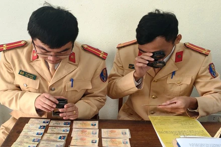 Cảnh sát giao thông sử dụng thiết bị chuyên dụng để quan sát, nhận diện dấu hiệu bất thường của giấy phép lái xe.