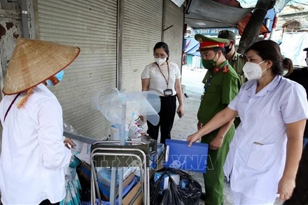 Lực lượng chức năng phường Đồng Xuân, quận Hoàn Kiếm phát hiện, lập biên bản xử lý một trường hợp bán rong khẩu trang không rõ nguồn gốc, vi phạm quy định phòng, chống dịch. (Ảnh: TTXVN)