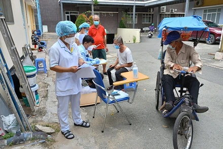 Nhân viên y tế kiểm tra kỹ thông tin trước bên ngoài phòng tiêm chủng.