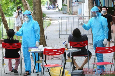 Nhân viên y tế lấy mẫu xét nghiệm người dân tại khu vực cách ly y tế phường Nam Đồng - quận Đống Đa. (Ảnh: DUY LINH)