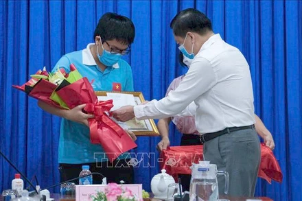 Phó Chủ tịch UBND TP Cần Thơ, Giám đốc Sở Giáo dục và Đào tạo Cần Thơ Dương Tấn Hiển chúc mừng và biểu dương học sinh Đặng Lê Minh Khang (Ảnh: TTXVN)