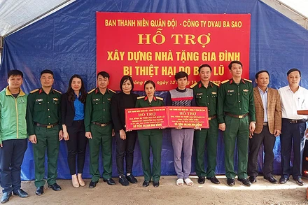 Sĩ quan dự bị Trần Hữu Diệu (áo xám trong ảnh) nhận nguồn hỗ trợ, động viên để xây dựng “Ngôi nhà 100 đồng” từ đại diện Ban Thanh niên quân đội ngay trên nền căn nhà cấp 4 vừa bị lũ cuốn trôi.