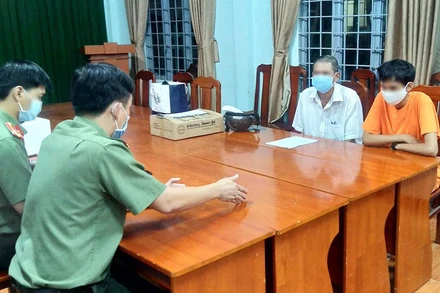 P.T (áo cam) làm việc với cơ quan chức năng.