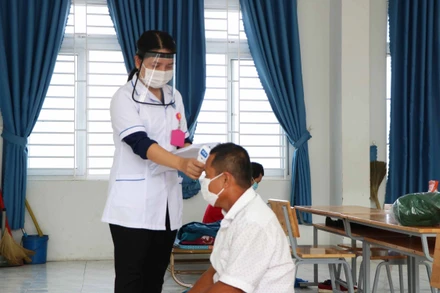 Nhân viên y tế đo thân nhiệt cho F0 tại khu cách ly tập trung huyện Thuận Nam ( Ninh Thuận).