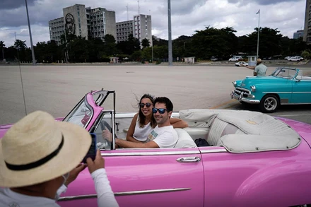 Du khách nước ngoài chụp ảnh với xe cổ tại thủ đô La Havana, Cuba. (Nguồn: Reuters)