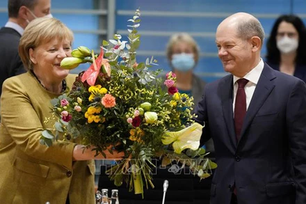 Ông Olaf Scholz tặng hoa cho Thủ tướng sắp mãn nhiệm Angela Merkel trước cuộc họp nội các ở Berlin, Đức, ngày 24/11/2021. (Ảnh: TTXVN)