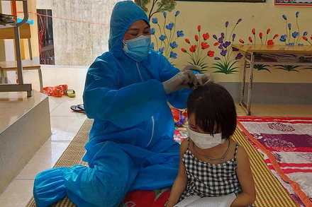 Giáo viên Trường Phổ thông dân tộc bán trú Tiểu học Thuận Hòa giúp đỡ học sinh trong khu cách ly. Ảnh: Nguyễn Thảo