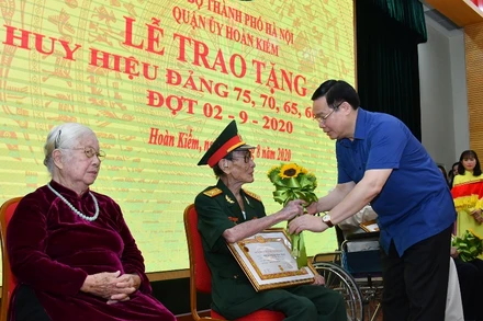 Ủy viên Bộ Chính trị, Bí thư Thành ủy Vương Đình Huệ trao Huy hiệu 75 năm tuổi Đảng các đồng chí đảng viên. (Ảnh: DUY LINH)