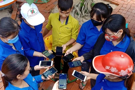 Thanh niên tình nguyện và người dân cùng cài đặt ứng dụng Bluezone ở Gia Lai.