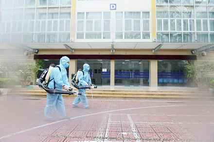 Nhân viên y tế phun thuốc khử khuẩn tại điểm thi Trường THPT Kim Liên (Hà Nội) sáng 6-8. Ảnh: PHẠM HÙNG