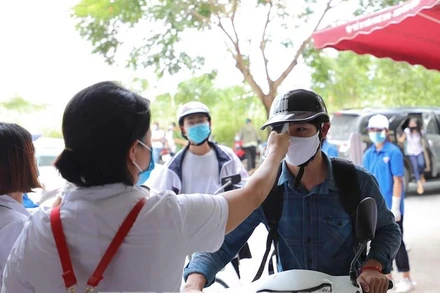 Cán bộ y tế kiêm tra thân nhiệt của thí sinh tham dự Kỳ thi tốt nghiệp THPT 2020 tại Điểm thi Trường THCS Nam Từ Liêm (Cầu Giấy, Hà Nội) chiều 8-8 (Ảnh: THANH TÙNG)