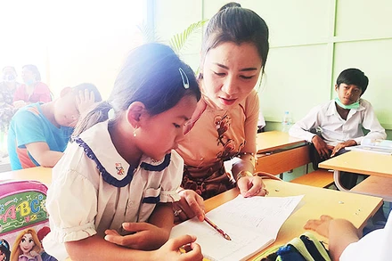 Cô giáo Dương Kim Huệ giúp bé làm quen với chữ Việt.