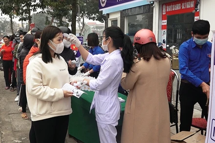 Nhân viên y tế kiểm tra thân nhiệt, cấp phát vật tư phòng dịch cho nhân dân ở huyện Hoằng Hóa.