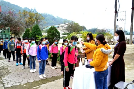 Học sinh Trường tiểu học Quang Kim (Bát Xát- Lào Cai) đeo khẩu trang, rhực hiện đo thân nhiệt và sát khuẩn tay trước khi vào lớp học. 