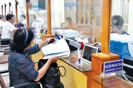 Cán bộ UBND quận Hoàn Kiếm tiếp nhận, hướng dẫn người dân làm thủ tục hành chính tại bộ phận “Một cửa”.