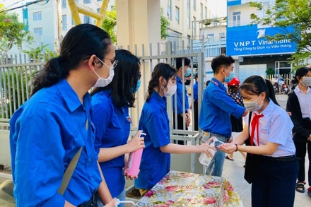 Thanh niên tình nguyện đo thân nhiệt học sinh trước khi vào điểm thi.