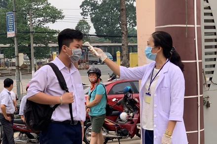 Cán bộ y tế đo thân nhiệt cho thí sinh tại Hội đồng thi Trường THCS Nguyễn Thị Minh Khai, TP Thủ Dầu Một.