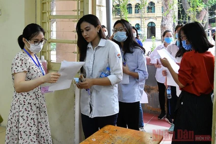Thí sinh gỡ khẩu trang để cán bộ coi thi kiểm tra, sau đó đeo khẩu trang vào phòng thi và trong suốt thời gian làm bài thi. Ảnh: THUỶ NGUYÊN
