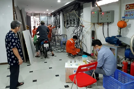 Nhân viên điện lực lắp đặt đồng hồ ở một chung cư mini trên địa bàn quận Ðống Ða.