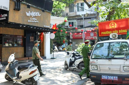 Công an phường Cửa Đông tuyên truyền nhắc nhở người dân phòng chống dịch. Ảnh: DUY LINH