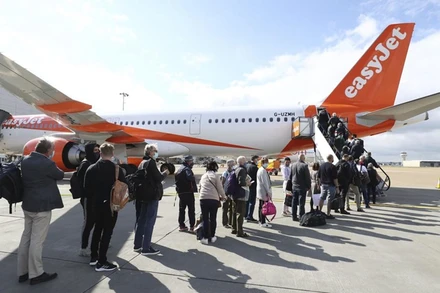 Hành khách chuẩn bị lên máy bay khởi hành từ sân bay Gatwick, Anh, tới Bồ Đào Nha, ngày 17-5. (Ảnh: AP)